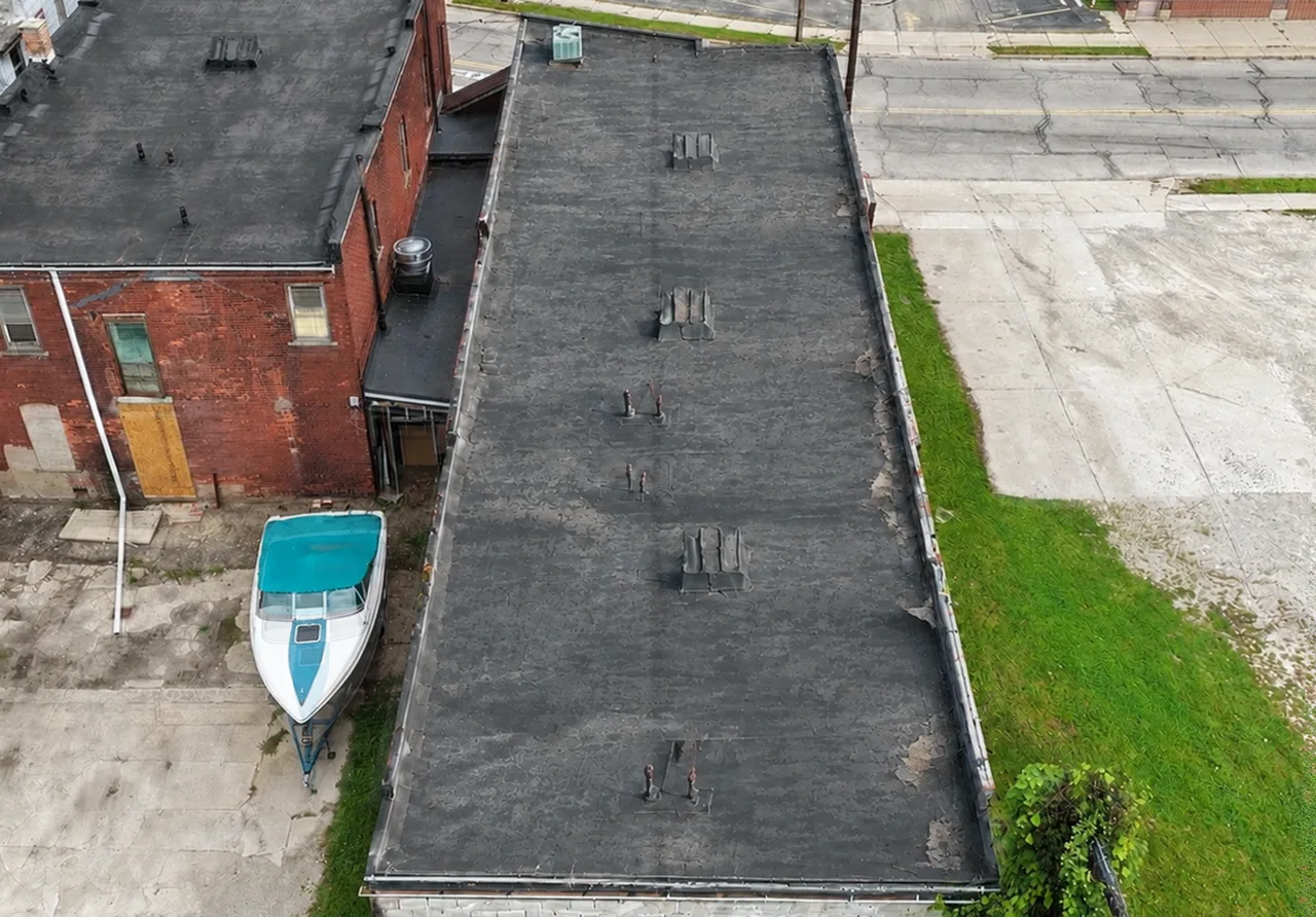 Before: a long commercial flat roof, worn and patched before, a new seamed membrane after